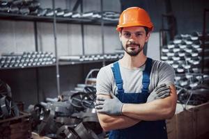 retrato de un joven trabajador con un casco en una gran planta metalúrgica. shiftman en el almacén de productos terminados foto