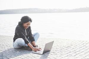 Young woman on the street working on laptop photo