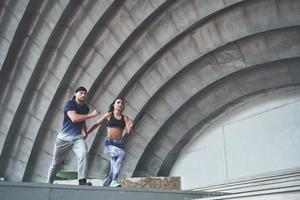 Young happy sports couple in the city street, performing parkour. photo