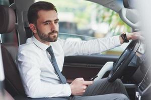 Beautiful young man in full suit while driving a car photo