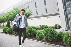 joven apuesto con una bolsa al hombro a toda prisa hacia el aeropuerto. foto