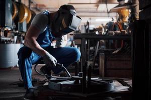 Portrait of a young worker at a large metalworking plant. The welder engineer works in a protective mask