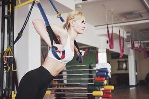 Women doing push ups training arms with trx fitness straps in the gym Concept workout healthy lifestyle sport photo
