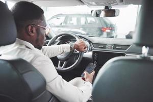 Young black businessman test drive new car. Rich african american man photo