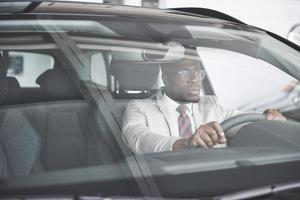 Vista frontal del apuesto hombre de negocios serio elegante africano conduce un coche foto