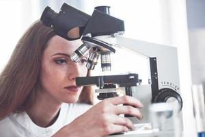 asistente de laboratorio con microscopio bombilla de cristalería de laboratorio con productos químicos. foto