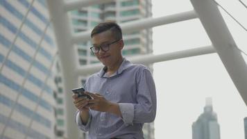 asiatischer Geschäftsmann, der lächelt und Handy verwendet, senden Sie eine Nachricht mit einem Freund. video