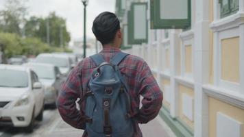 portret van knappe jonge aziatische man solo-toeristen die rondkijken op straat in thailand. video