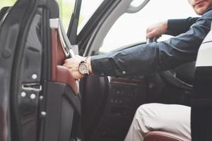 Beautiful young man in full suit while driving a car photo