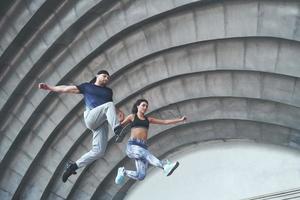 Young happy sports couple in the city street, performing parkour. photo