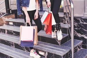 Two young woman carrying shopping bags while walking on the stairs after visiting the stores photo