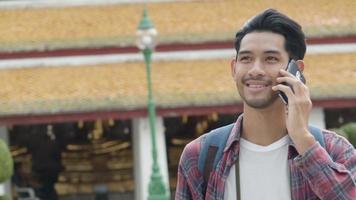 asiatischer Mann, der mit Freunden im Tempel von Thailand geht und mit dem Handy spricht. video
