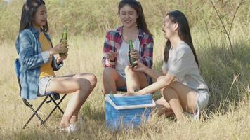 Aziatische vrouw gelukkige vrienden kamperen in de natuur plezier samen bier drinken en rammelende glazen.