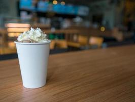 Hot mocha with whipping cream in paper cup on wooden table photo
