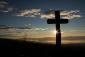 Silhouette of catholic cross and sunrise photo