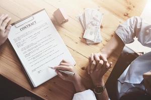 el cliente sostiene un bolígrafo y lee las condiciones para firmar un contrato de compraventa de vivienda con los documentos del seguro del hogar con el vendedor.