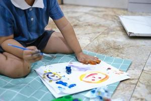 Focus on hands on paper, early childhood learning by using paints and brushes to build imagination and enhance skills on the board. photo