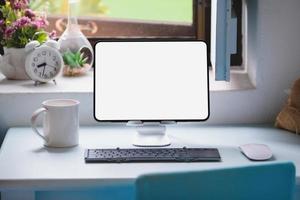 tableta para trabajar en un escritorio de madera, una pantalla de tableta en blanco puede agregar texto u otros medios. foto