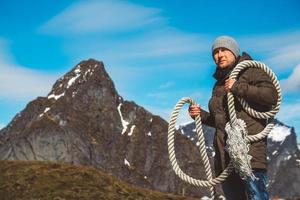 Man with a rope on his shoulder against background of the mountains and blue sky photo