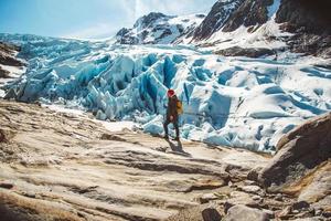 Hombre viajero de pie sobre una roca en el fondo de un glaciar, montañas y nieve