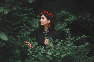 Woman in black dress and red decorations on background of forest photo