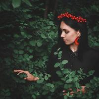 Mujer en vestido negro y adornos rojos sobre fondo de bosque foto