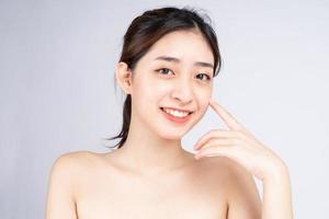 Hermosa joven asiática con piel limpia y fresca sobre fondo blanco. foto