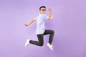 Retrato de un hombre asiático saltando, aislado sobre fondo púrpura foto