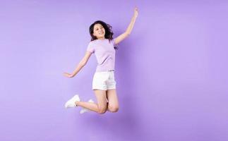 Young asian girl jumping up on purple background photo