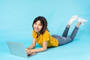 full body portrait of playful asian girl lying on blue background photo