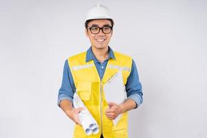 Sonriente joven ingeniero civil asiático con casco casco de pie sobre fondo blanco aislado. concepto de servicio mecánico.