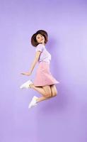Young asian girl jumping up on purple background photo