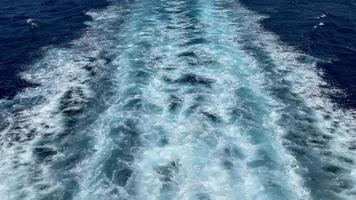 Perspective of a person sailing on a big ship and cruising across the vast blue sea as it creates ripples and waves on the deep waters, tracking backwards video