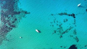 vista dall'alto di una spiaggia di sabbia bianca piena di gente che si gode una calda giornata di sole vicino a diversi alberi sul campo e scogliere con barche a vela sul mare video