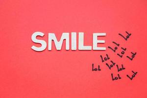 Sonrisa palabra con letras de madera blancas sobre fondo rojo. foto