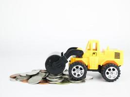 Coche de carretera de presión de juguete con monedas sobre fondo blanco, concepto de negocio foto