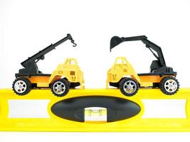 Toy Crane car and Mechanical digger with building level on white background, Engineering construction concept photo