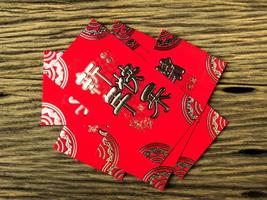 Red envelope on wooden background with February for gift Chinese New Year. Chinese text on envelope meaning Happy Chinese New Year photo