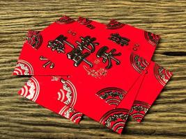 Red envelope on wooden background with February for gift Chinese New Year. Chinese text on envelope meaning Happy Chinese New Year photo