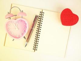 Top view of notebook alarm clock and pen with red heart, Vintage filter photo