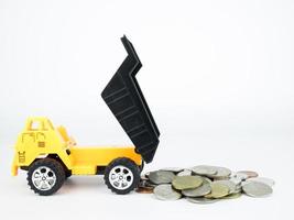 Camión de juguete con monedas sobre fondo blanco, concepto de negocio foto
