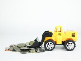 Toy Bulldozers with coins on white background, Business concept photo