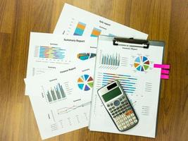 Cuadro de informes comerciales y análisis de gráficos financieros con calculadora en la mesa foto