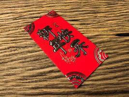 Red envelope on wooden background with February for gift Chinese New Year. Chinese text on envelope meaning Happy Chinese New Year photo