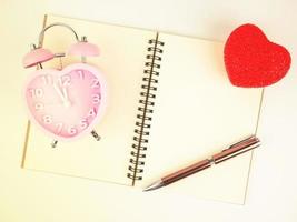 Top view of notebook alarm clock and pen with red heart, Vintage filter photo