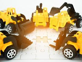 Toy Bulldozer, Pressure road,  Truck crane, Mechanical digger, Forklift and jigsaw puzzle with teamwork and Engineering construction concept photo