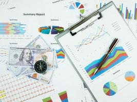 Business report chart and Financial graph analysis with dollar money, pen and compass on table photo
