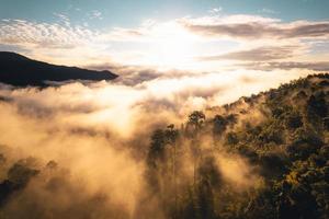 el sol sale en la niebla y las montañas por la mañana foto