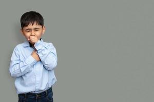 Cute little boy is coughing, on gray background