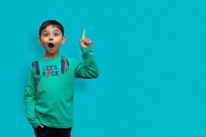 Wow look, advertise here Portrait of amazed cute little boy pointing to empty place on background, surprised schoolboy showing copy space photo